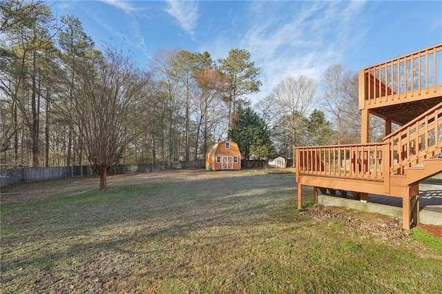 view of yard with a storage shed, an outbuilding, fence, and a wooden deck