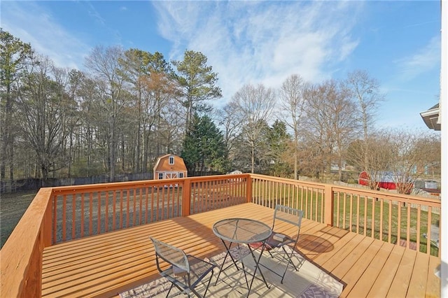 wooden deck featuring a shed, a fenced backyard, and an outbuilding