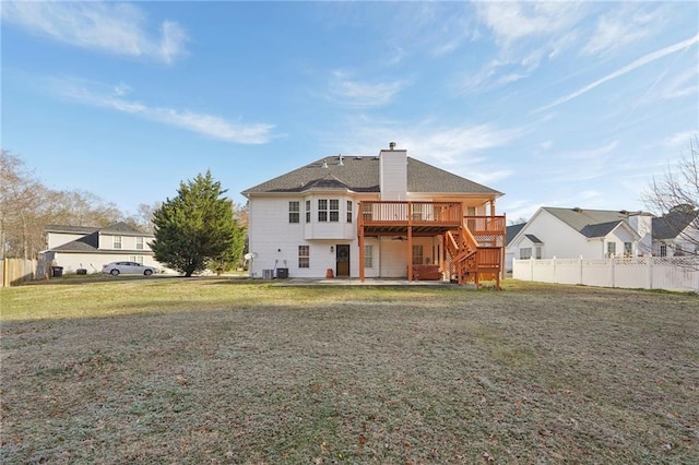 rear view of house with stairway, a wooden deck, a lawn, and fence