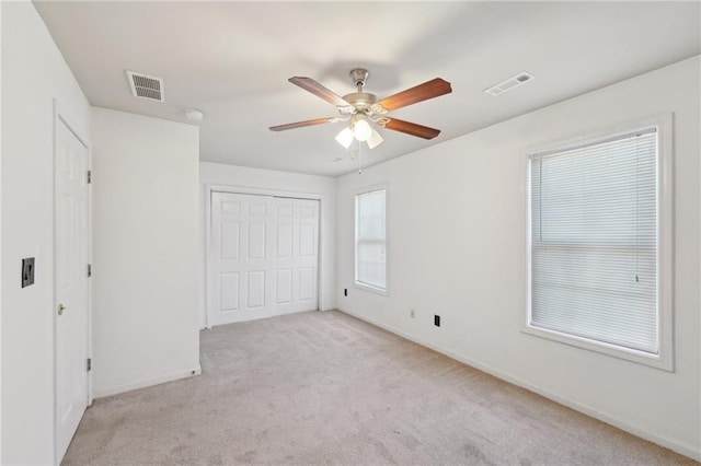 unfurnished bedroom with light carpet, a closet, visible vents, and baseboards