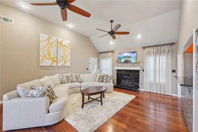 living area with dark wood-style floors, a healthy amount of sunlight, visible vents, and vaulted ceiling