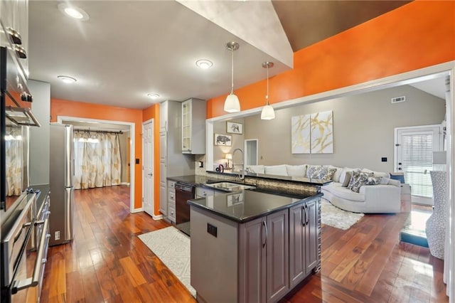 kitchen featuring black dishwasher, glass insert cabinets, open floor plan, a sink, and a peninsula