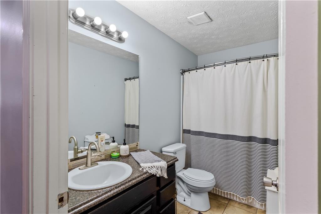 bathroom with tile patterned floors, a textured ceiling, toilet, vanity, and a shower with shower curtain