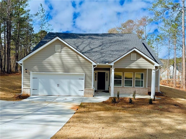 view of front facade with driveway, roof with shingles, covered porch, a garage, and brick siding