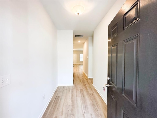 hall featuring baseboards, visible vents, and light wood finished floors