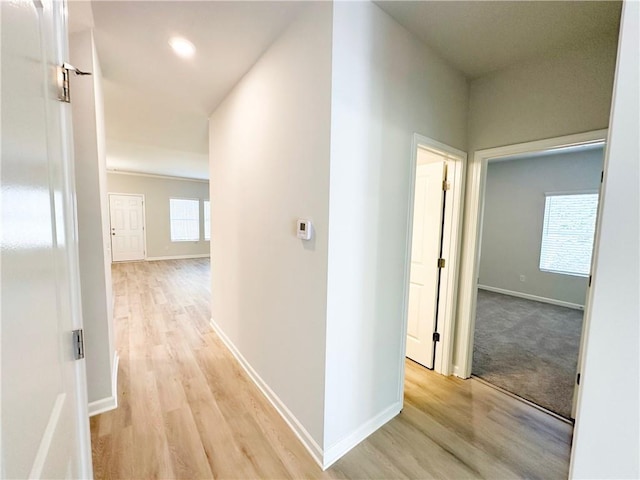 hall with baseboards and light wood finished floors