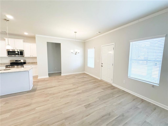 interior space featuring crown molding, baseboards, a chandelier, light wood-type flooring, and a wealth of natural light