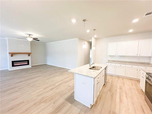 kitchen with visible vents, a sink, tasteful backsplash, white cabinetry, and light wood finished floors