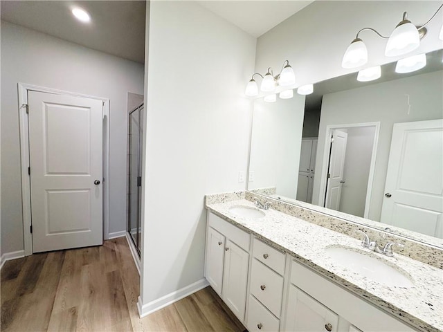 bathroom featuring a shower stall, wood finished floors, and a sink