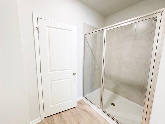 bathroom with wood finished floors and a stall shower