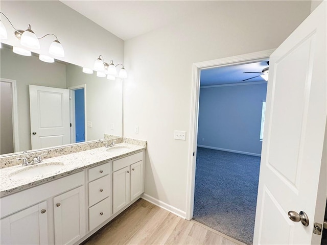 full bath featuring a sink, baseboards, wood finished floors, and double vanity