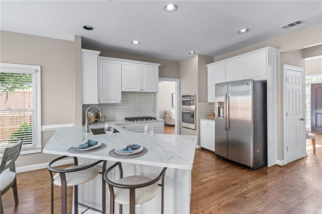 4648 Glenshire Pl, Atlanta, GA 30338 - kitchen featuring appliances with stainless steel finishes, a peninsula, white cabinetry, light stone counters, and recessed lighting
