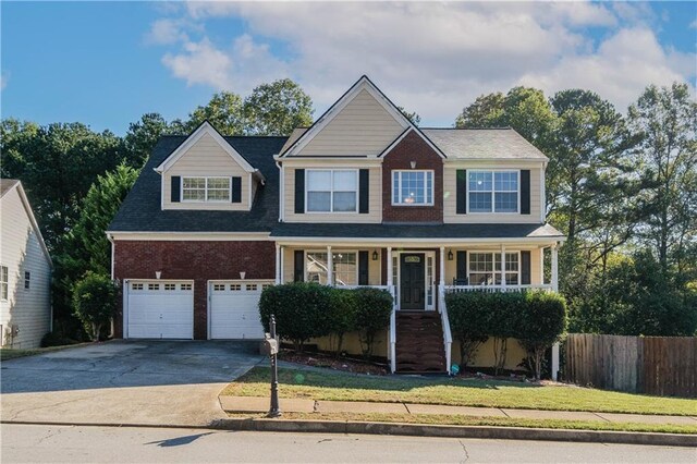 view of front of property with a garage, a front lawn, and covered porch