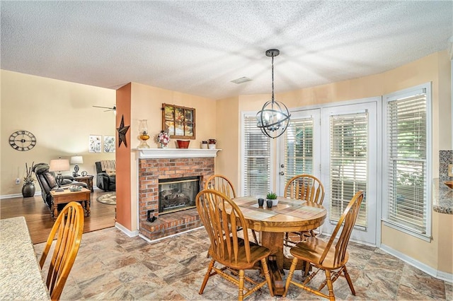 2130 Hampton Trl SE, Conyers, GA 30013 - dining space featuring a chandelier, a textured ceiling, a brick fireplace, and light stone finish flooring