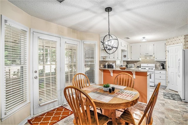 2130 Hampton Trl SE, Conyers, GA 30013 - dining space featuring a chandelier, a textured ceiling, and light stone finish flooring