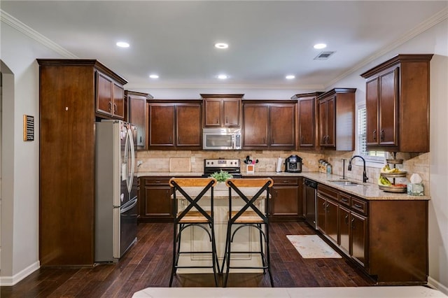 kitchen with appliances with stainless steel finishes, a sink, dark wood finished floors, a center island, and dark brown cabinets