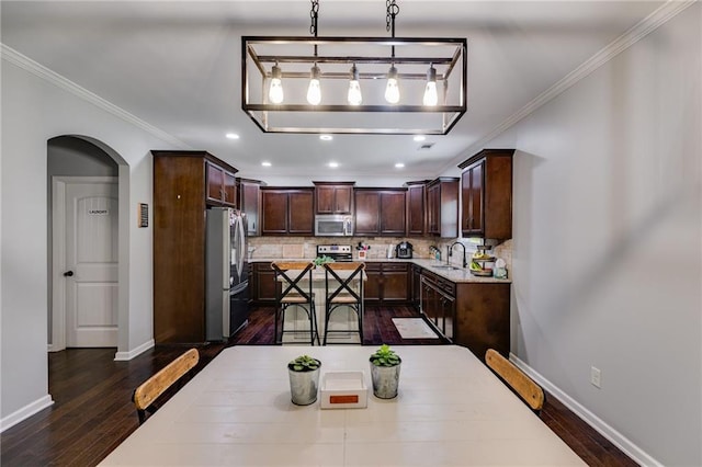 dining area featuring arched walkways, dark wood finished floors, ornamental molding, baseboards, and recessed lighting