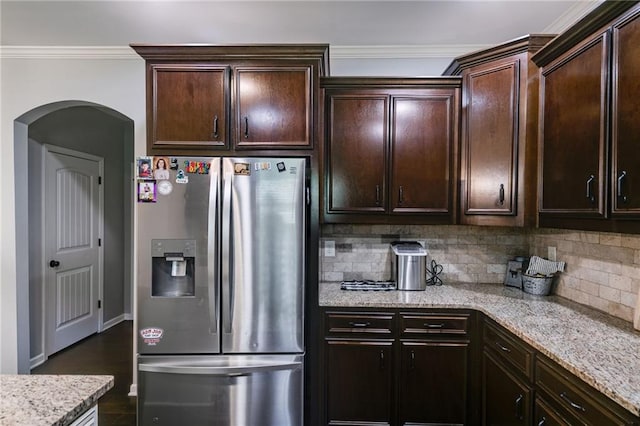 kitchen with stainless steel fridge with ice dispenser, arched walkways, light stone counters, decorative backsplash, and dark brown cabinetry