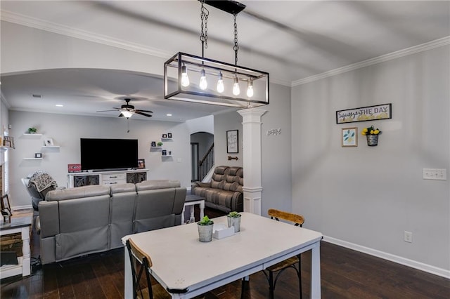 dining area featuring decorative columns, dark wood-type flooring, a ceiling fan, crown molding, and baseboards