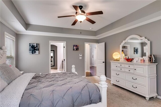 bedroom with a raised ceiling, light carpet, arched walkways, ceiling fan, and baseboards