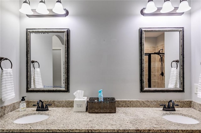 bathroom with a tile shower and double vanity