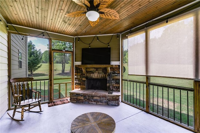 sunroom / solarium featuring a ceiling fan and an outdoor stone fireplace