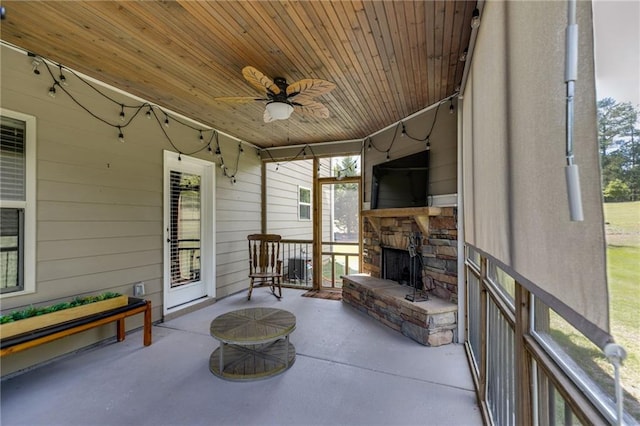 sunroom / solarium featuring an outdoor stone fireplace, a ceiling fan, and healthy amount of natural light