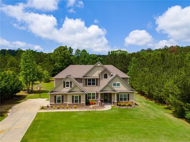 craftsman inspired home featuring board and batten siding, a view of trees, concrete driveway, a front yard, and stone siding