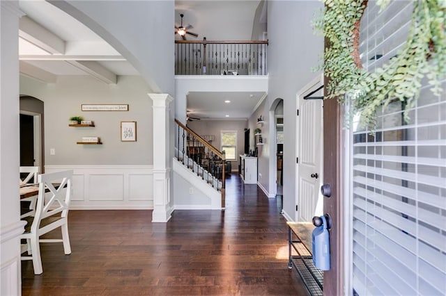 foyer featuring a ceiling fan, arched walkways, hardwood / wood-style floors, stairway, and a high ceiling