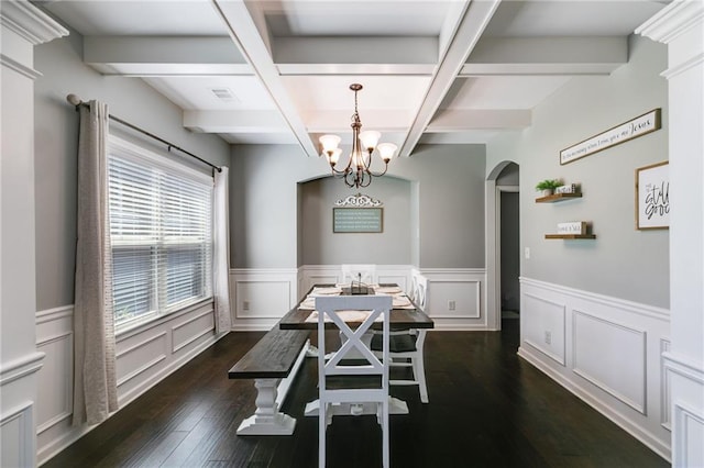 dining space featuring arched walkways, dark wood finished floors, a chandelier, beam ceiling, and coffered ceiling