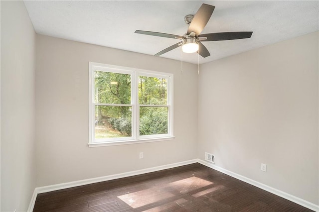 spare room featuring baseboards, a ceiling fan, dark wood-style floors, and visible vents
