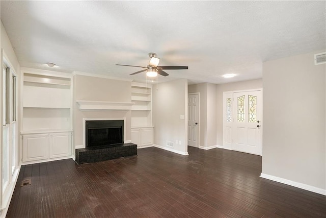 unfurnished living room with built in features, a brick fireplace, baseboards, ceiling fan, and dark wood-type flooring