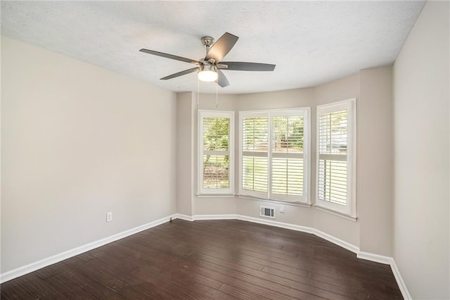 spare room with visible vents, baseboards, ceiling fan, a textured ceiling, and dark wood finished floors