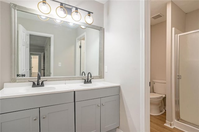 bathroom featuring toilet, a shower stall, a sink, and wood finished floors