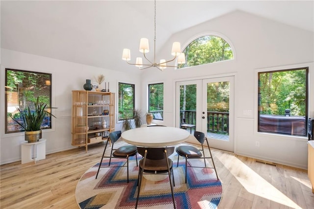 dining room with high vaulted ceiling, light hardwood / wood-style flooring, french doors, and a notable chandelier