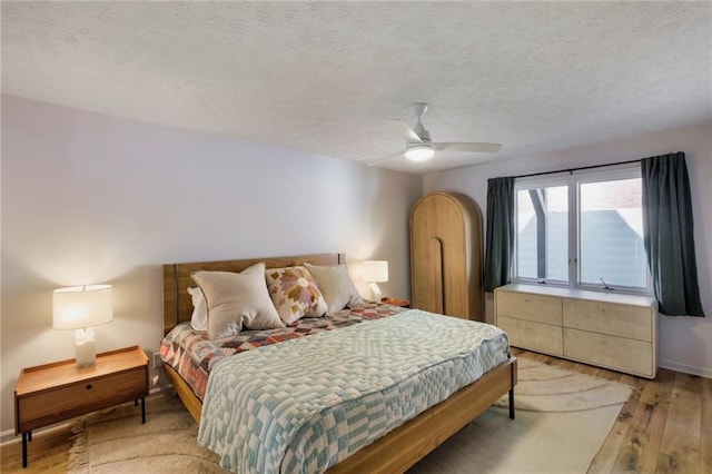 bedroom with ceiling fan, a textured ceiling, and light hardwood / wood-style floors