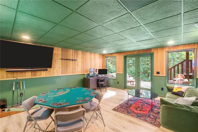 game room with french doors, wooden walls, a paneled ceiling, and hardwood / wood-style floors