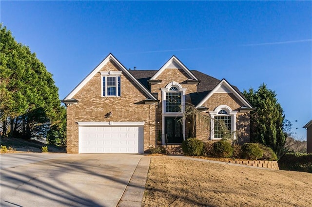 traditional-style house with a garage, driveway, and brick siding