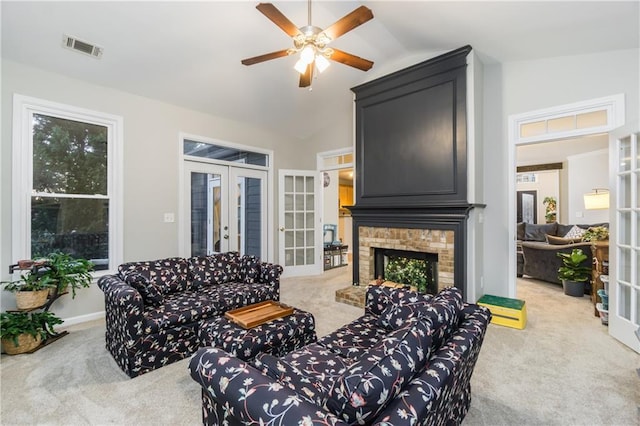 living room with lofted ceiling, french doors, a brick fireplace, and light colored carpet