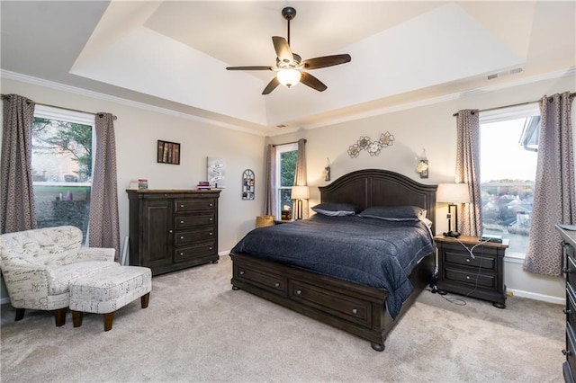 bedroom featuring a raised ceiling, light carpet, visible vents, and multiple windows