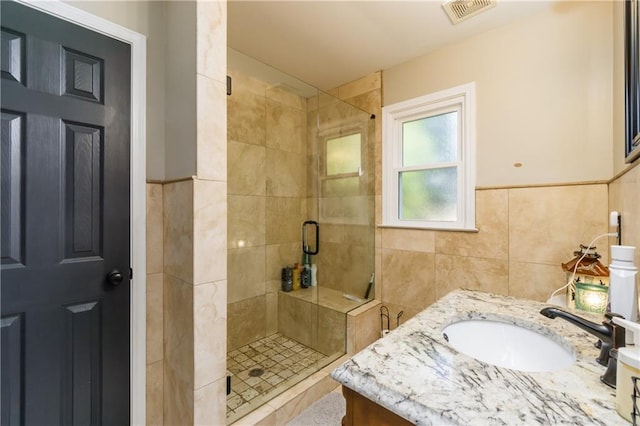 full bathroom featuring visible vents, vanity, a shower stall, and tile walls