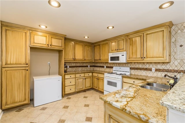 kitchen with white appliances, tasteful backsplash, light stone countertops, a sink, and recessed lighting