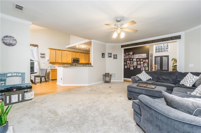 living area featuring ornamental molding, light colored carpet, visible vents, and a ceiling fan