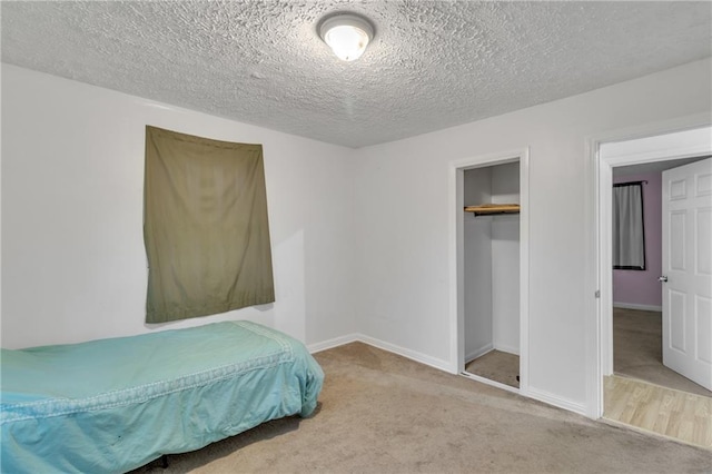 carpeted bedroom featuring a closet, a textured ceiling, and baseboards