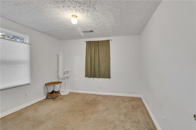 unfurnished room featuring a textured ceiling, carpet, visible vents, and baseboards