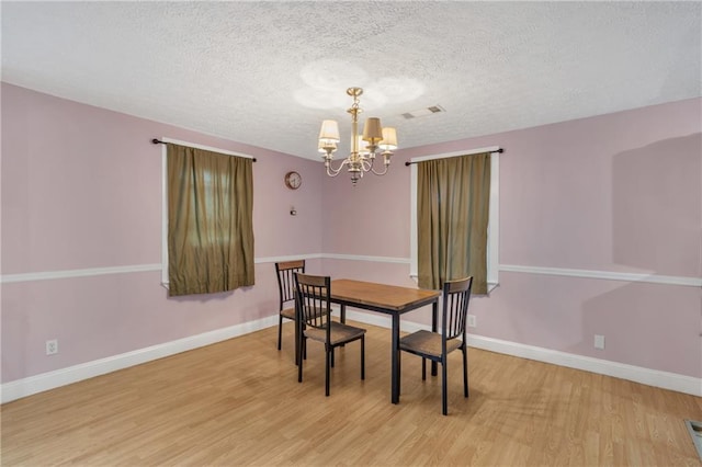 dining area with a chandelier, a textured ceiling, wood finished floors, and baseboards