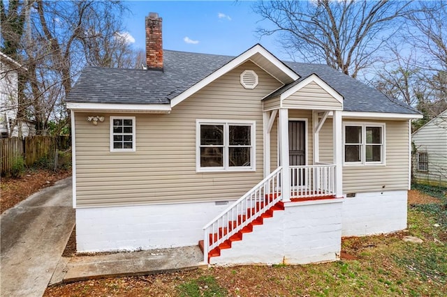 bungalow-style home featuring a shingled roof, fence, a chimney, and crawl space