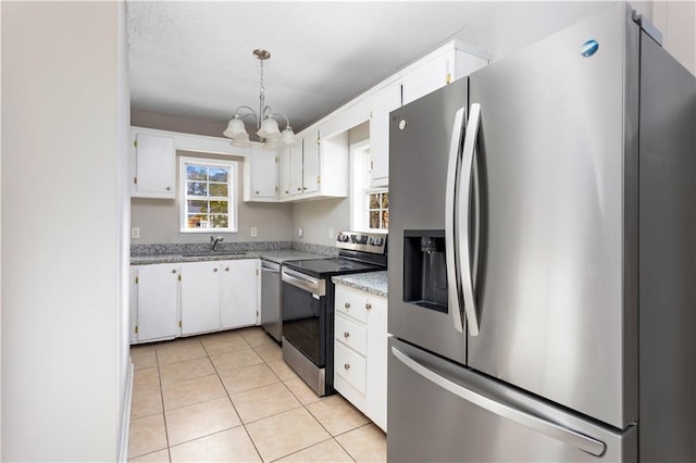 kitchen featuring a sink, white cabinetry, stainless steel appliances, light tile patterned floors, and a chandelier