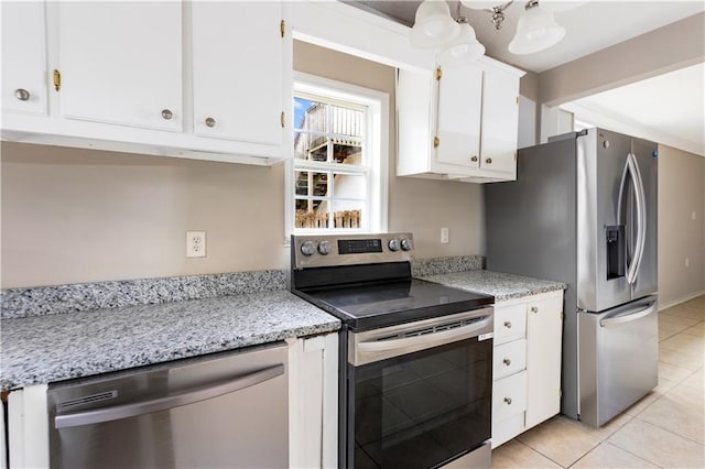 kitchen featuring light tile patterned floors, white cabinets, appliances with stainless steel finishes, and light stone counters