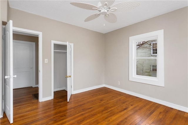 unfurnished bedroom featuring a closet, baseboards, hardwood / wood-style floors, and a ceiling fan